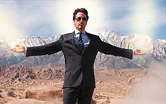 Man in black suit with arms outstretched in a desert landscape