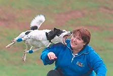 Woman in blue jacket playing with a white and black dog
