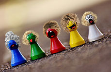 Five small, colorful figurines lined up on a surface, each with a different color and facial expression.
