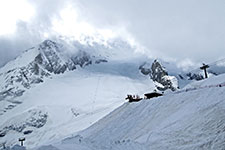 Snow-covered mountain slope with ski lifts and rugged peaks in the background