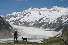 Hiker with dog on a mountain ridge overlooking a glacier