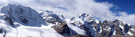 Snow-covered mountain peaks with a blue sky and clouds
