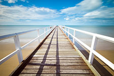 A long wooden pier with white railings extending into the sea