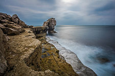 A dramatic rocky outcrop by the ocean with waves crashing below