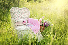 A floral chair with a hat and flowers in a grassy field