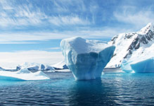Large iceberg in the ocean with snow-covered mountains