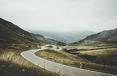 A winding road through a mountainous landscape with cloudy skies