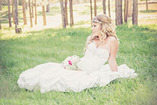 Bride in a white wedding dress sitting on grass with a bouquet
