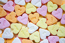 Pastel-colored conversation hearts with messages like 'LOVE' and 'HUG'