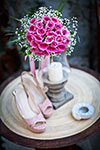 Pink high heels and flowers on a wooden table with a candle
